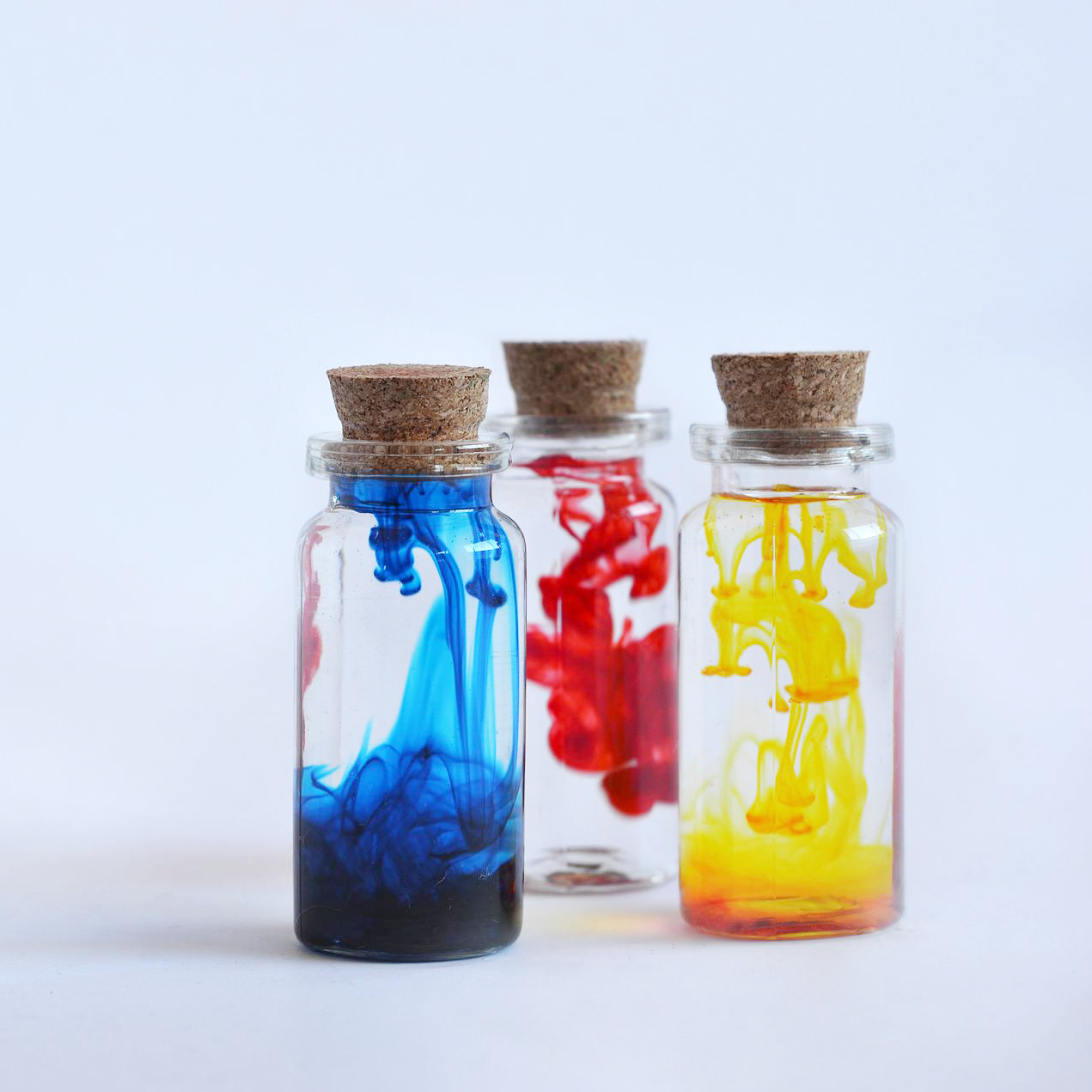 Three small glass bottles with colored liquid inside for National Chemistry Week - STEM Calendar For Educators: Month By Month STEM Projects