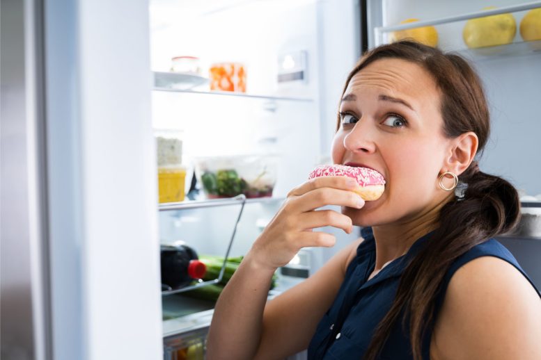 Hungry Woman Eating Donut - New Research Indicates That Loneliness Triggers Sugar Cravings In Women